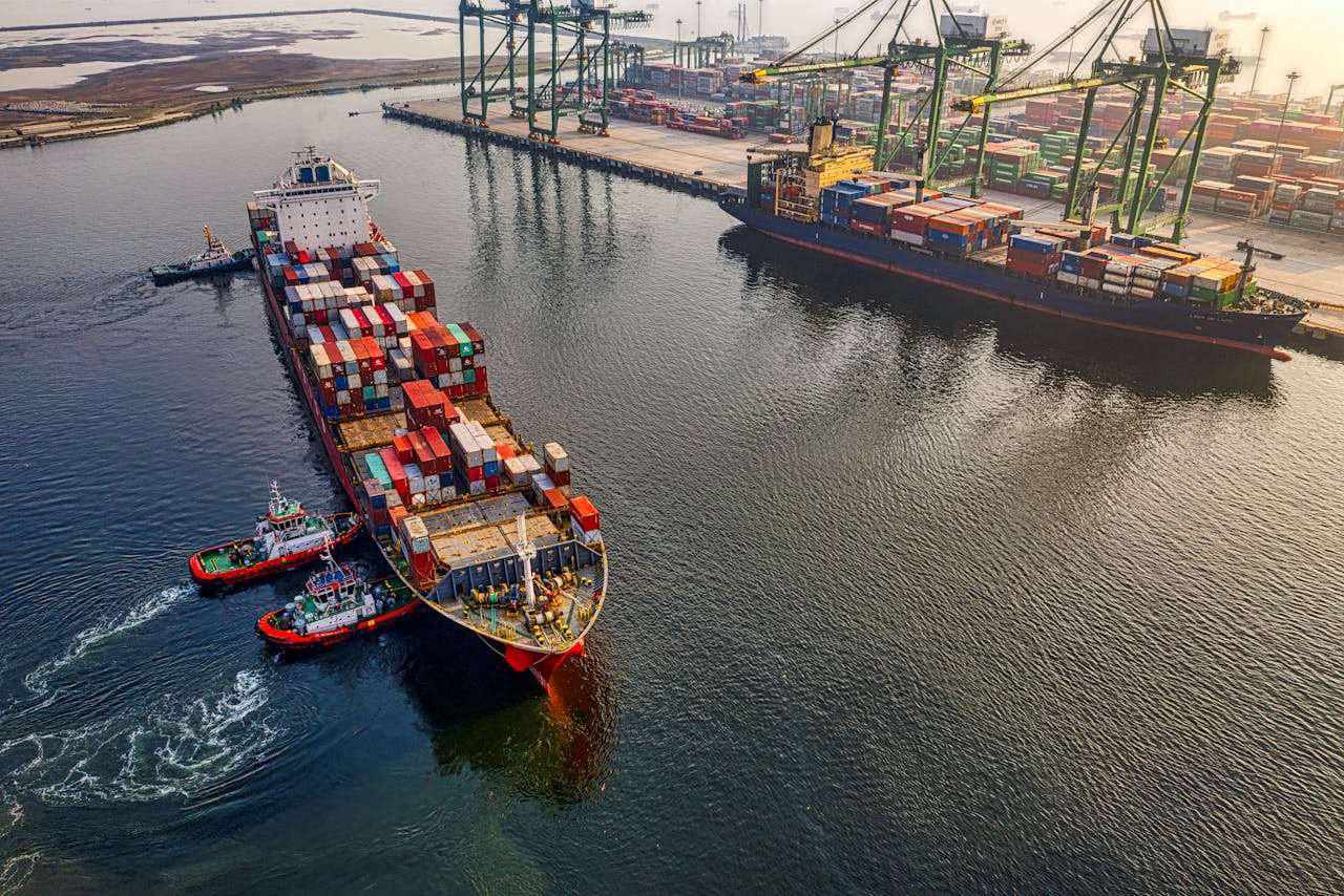 heros-img Aerial shot of cargo ships and cranes at North Jakarta port, showcasing global shipping and logistics.
